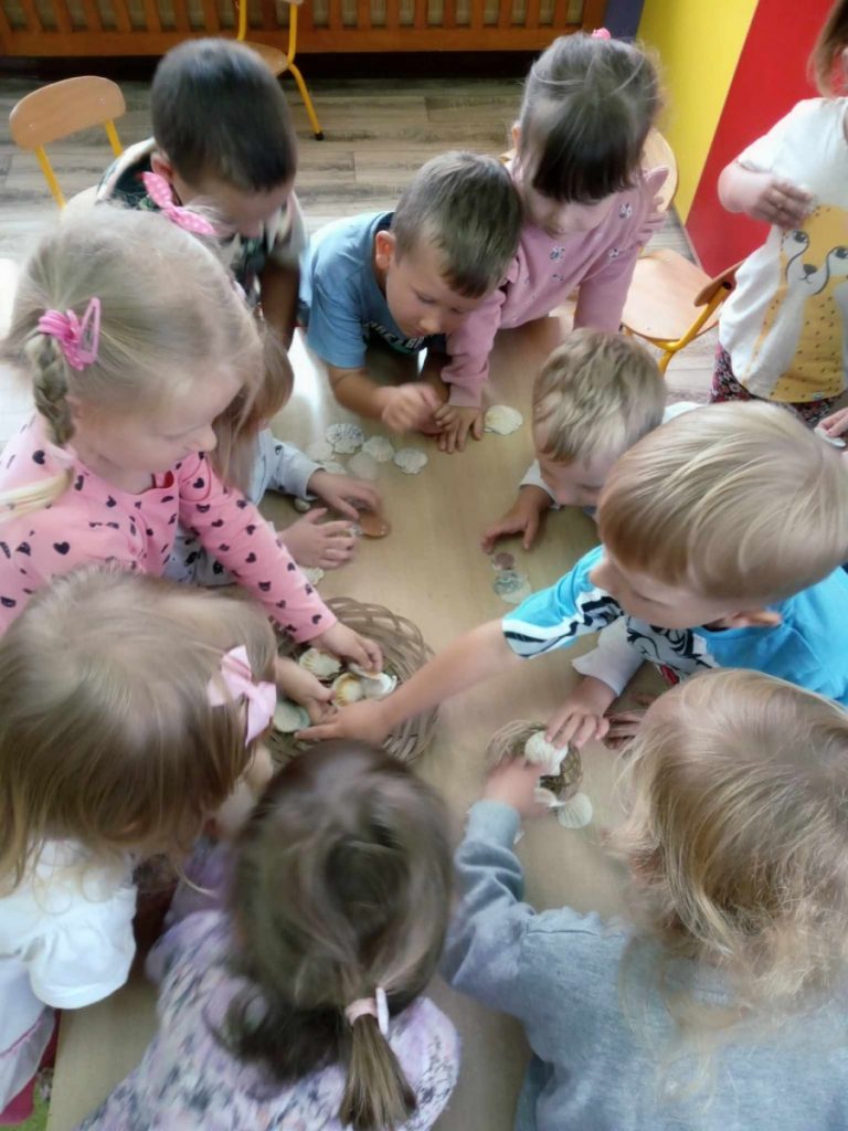 Na zdjęciu dzieci oglądają skarby morza- muszelki