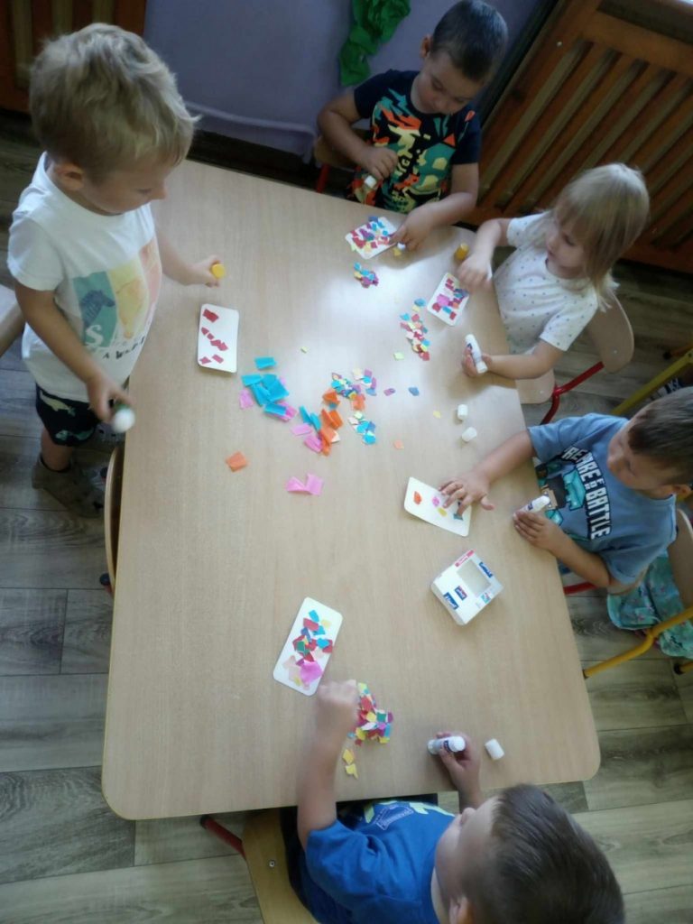 Na zdjęciu dzieci wykonują pracę plastyczną przy stoliku-lody