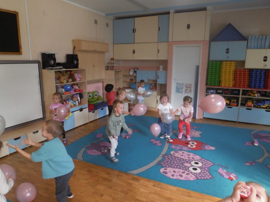 na zdjęciu widać grupę dzieci, która  na dywanie bawi się balonami