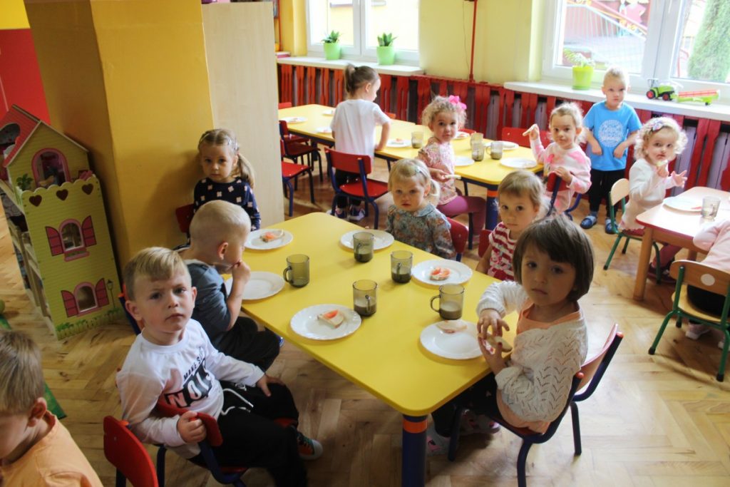 Dzieci siedzą przy stoliku i jedzą śniadanie 