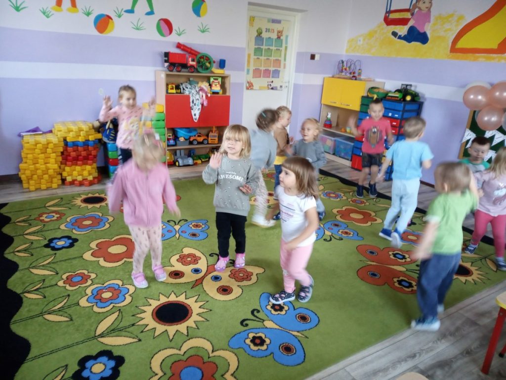 Na zdjęciu dzieci tańczą na dywanie.