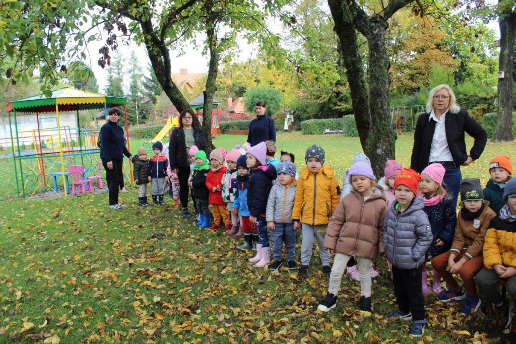 grupa dzieci wraz z nauczycielkami stoi na placu zabaw