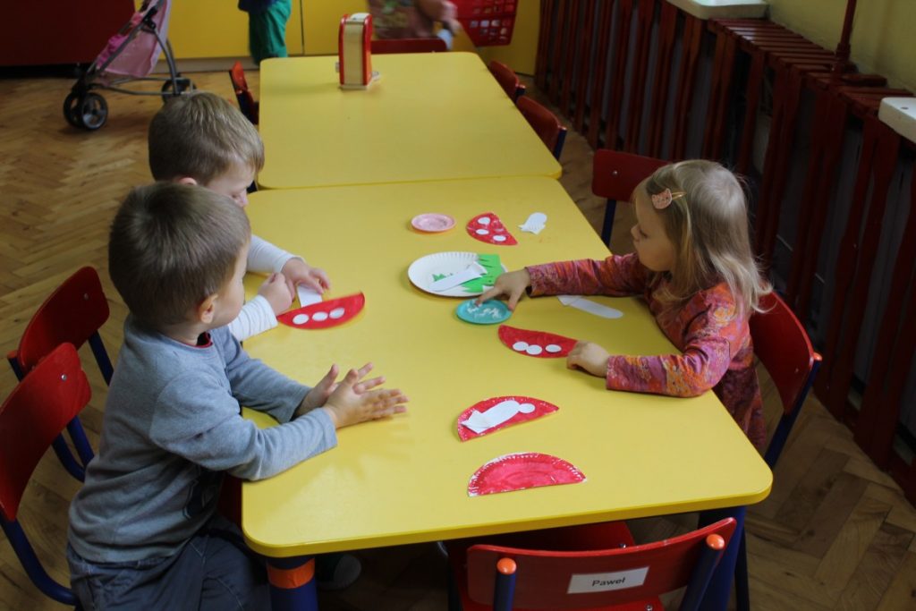 dzieci przy stolikach wykonują muchomory z papieru