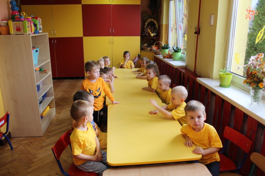 Dzieci w żółtych podkoszulkach siedzą przy stole