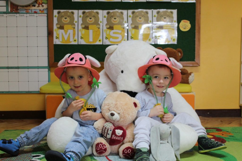 Dwójka dzieci w różowych kapeluszach z pluszowymi misiami