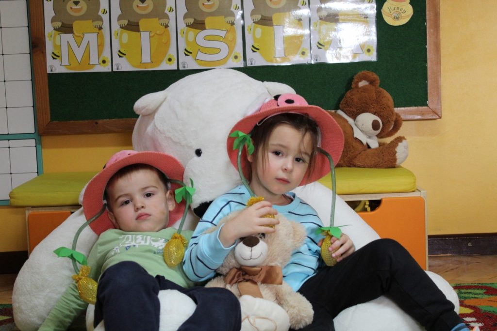 Dwójka dzieci w różowych kapeluszach z pluszowymi misiami