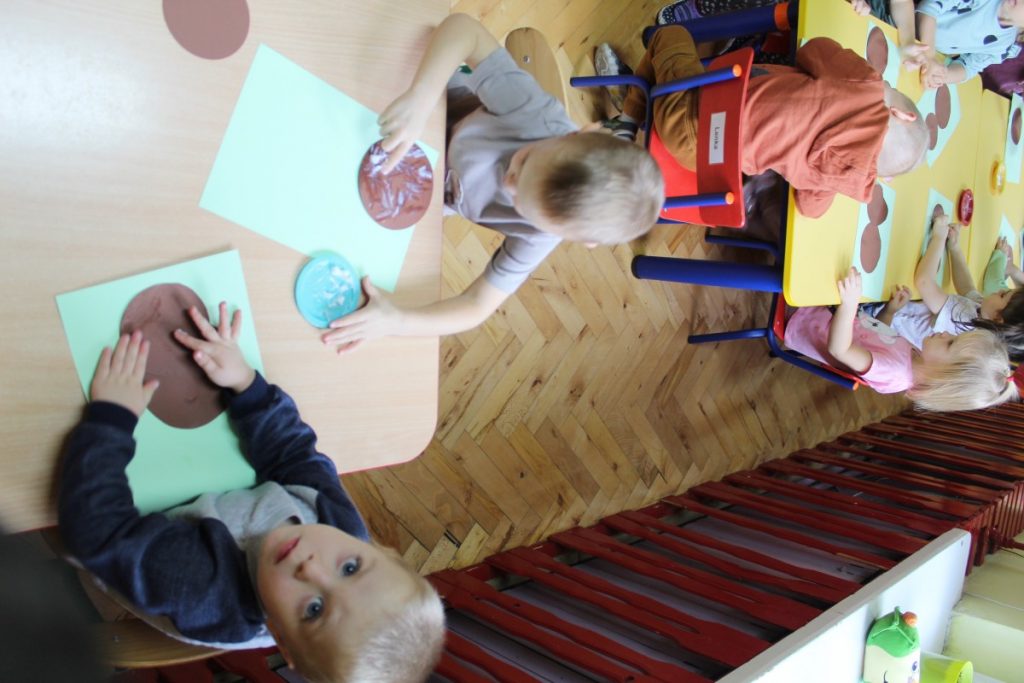 Dzieci przy stoliku układają misia z brązowych kółek