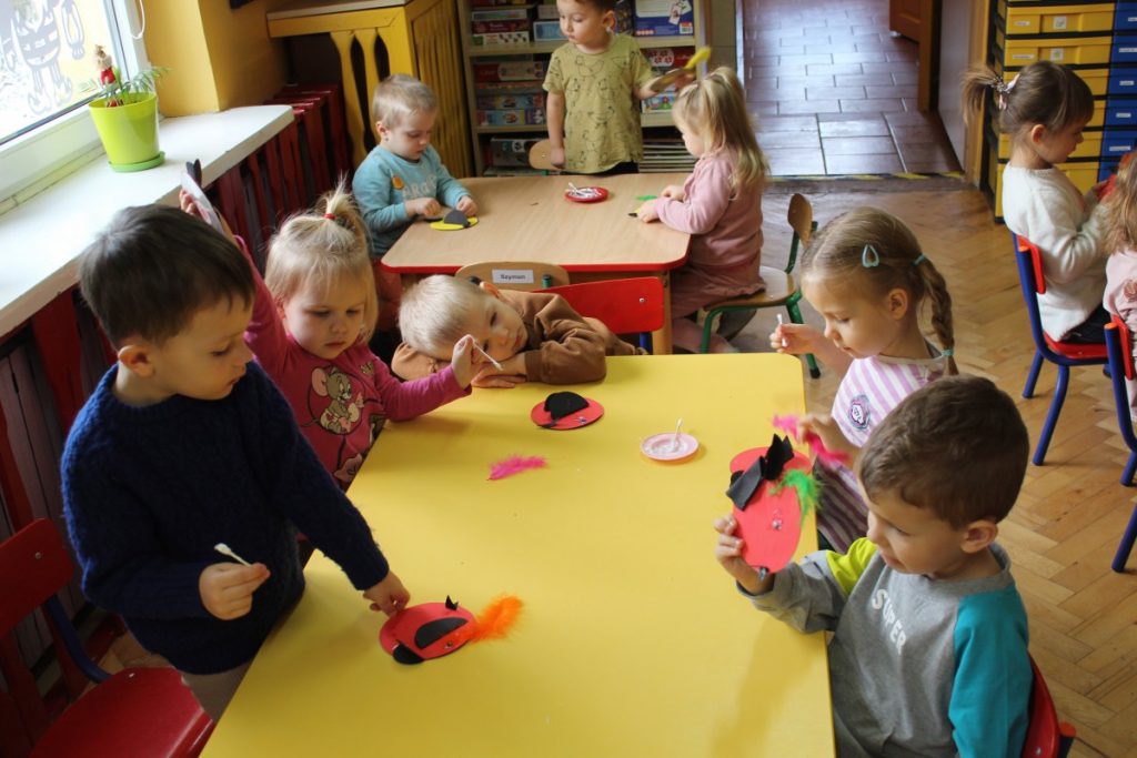 Dzieci przy stoliku kleją ptaszki z płyt CD
