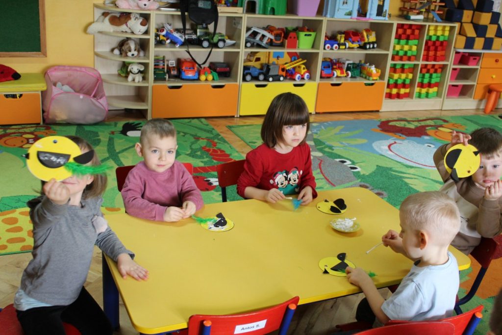 Dzieci przy stoliku kleją ptaszki z płyt CD