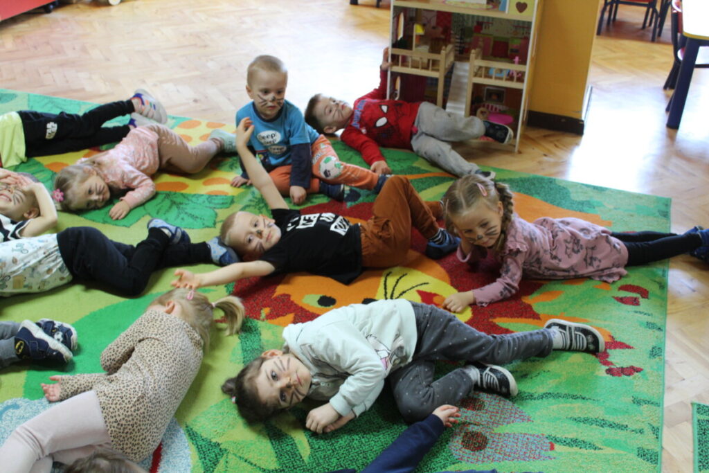 Dzieci na dywanie turlają się