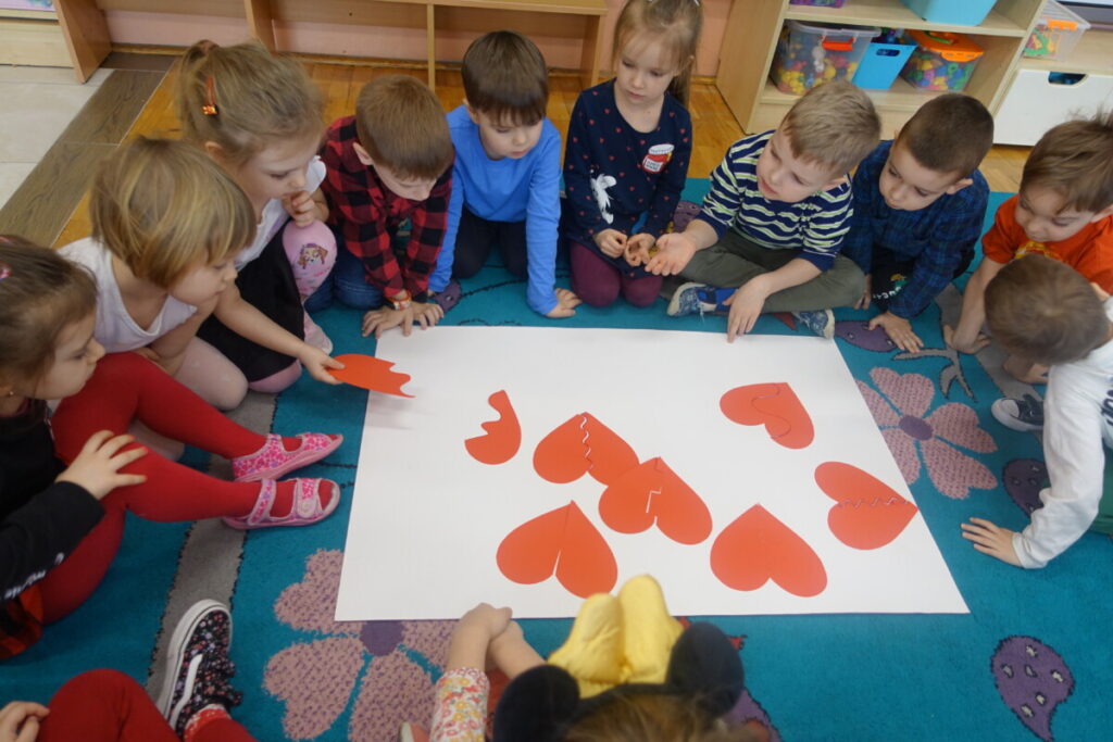 dzieci na dywanie układają serca podzielone na części