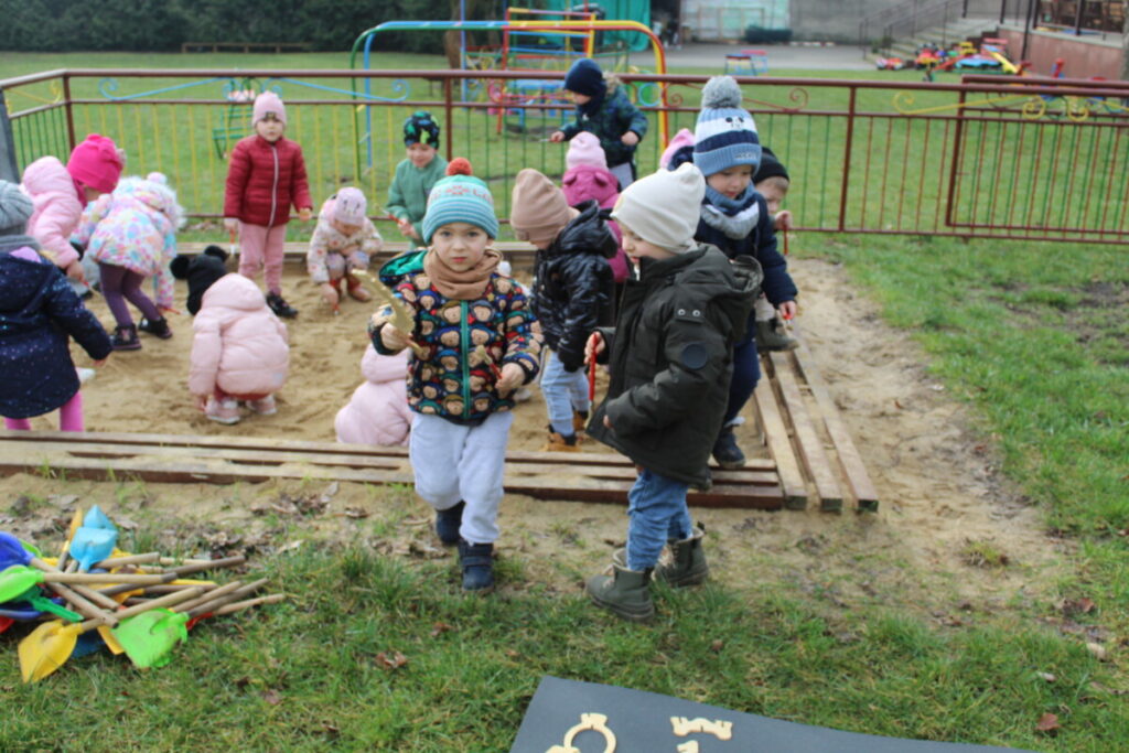 Grupka dzieci szuka w piaskownicy kości dinozaurów. Zabawa w paleontologów