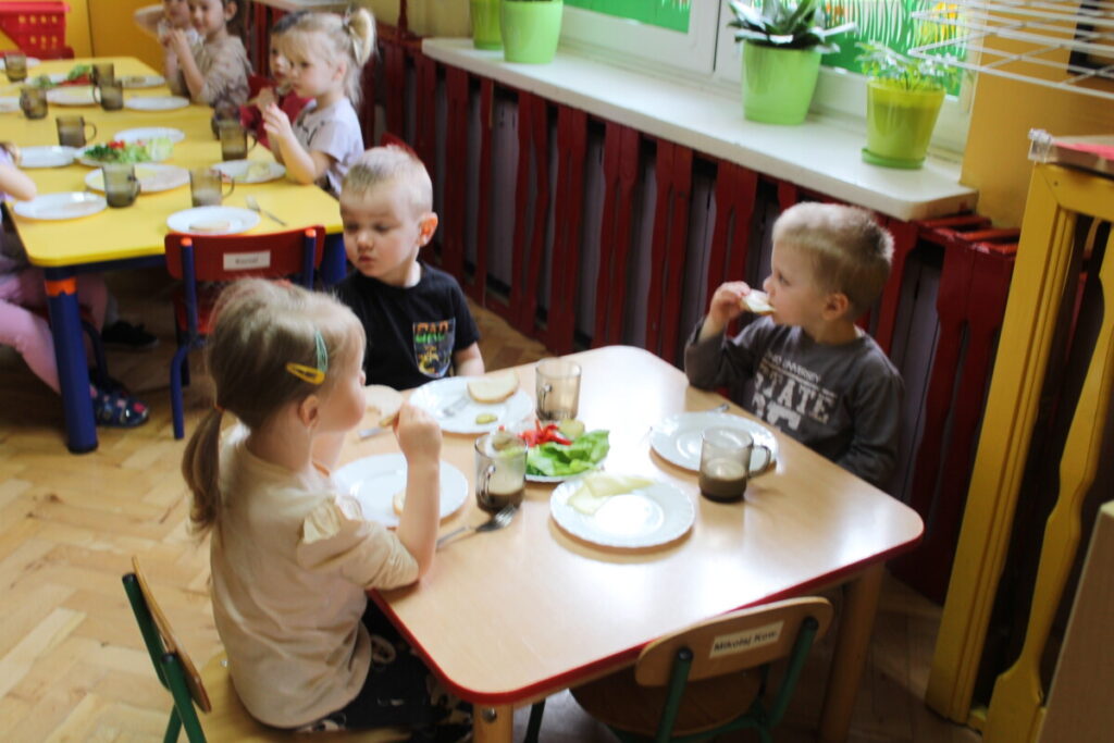 Dzieci przy stoliku robią sobie samodzielnie kanapki