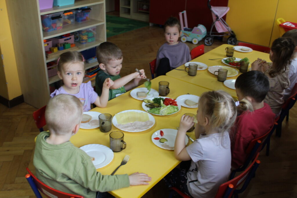 Dzieci przy stoliku robią sobie samodzielnie kanapki