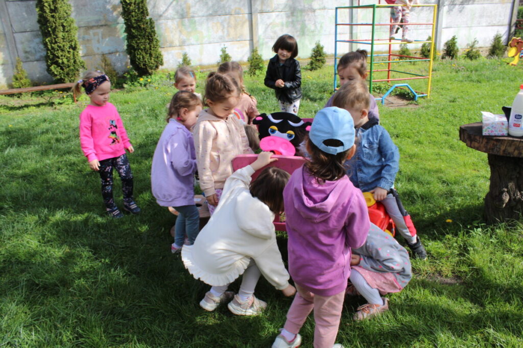 Dzieci na podwórku karmią zabawkową krowę